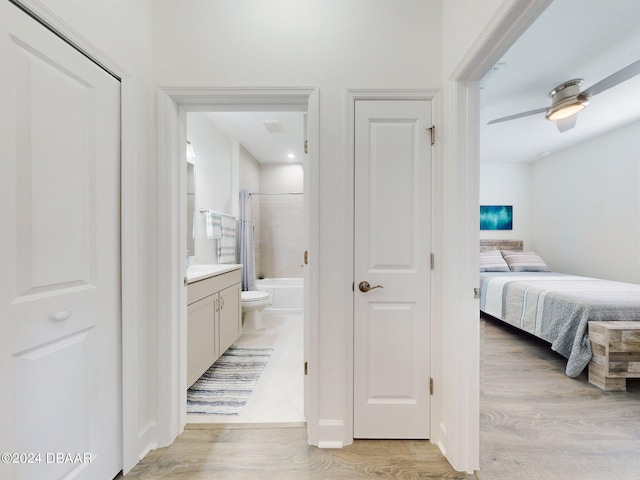 bedroom featuring connected bathroom, light hardwood / wood-style flooring, and ceiling fan