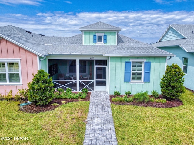 view of front facade with a front yard and a sunroom