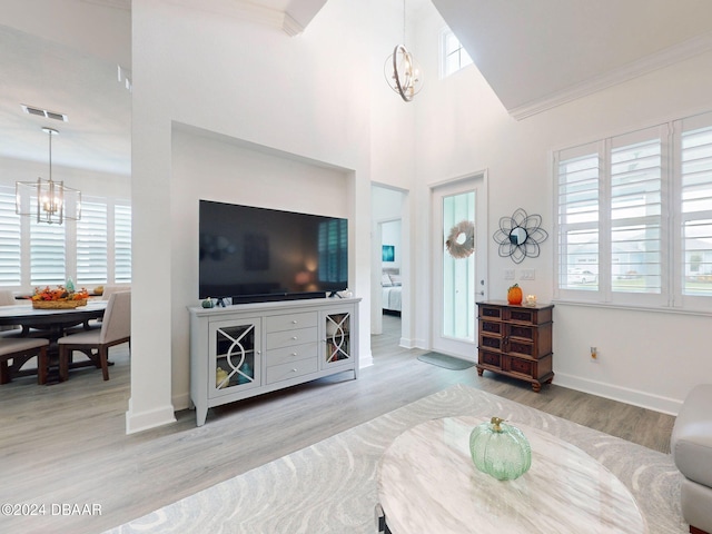 living room with ornamental molding, light hardwood / wood-style floors, a chandelier, and plenty of natural light