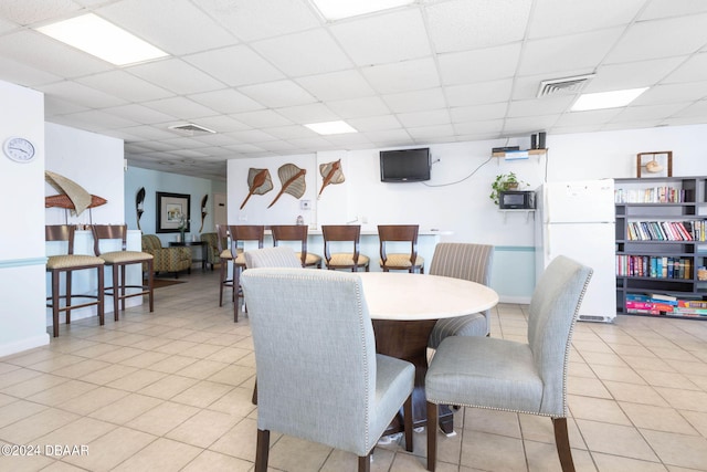 dining area featuring a paneled ceiling and light tile patterned flooring