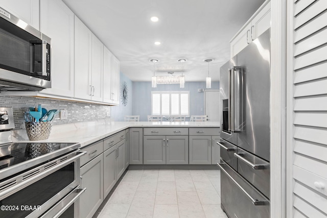 kitchen featuring white cabinets, gray cabinets, appliances with stainless steel finishes, and decorative light fixtures