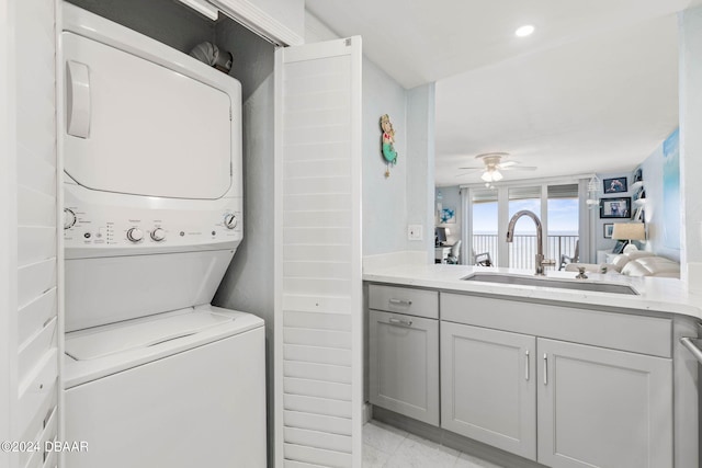 laundry area with stacked washer / dryer, sink, and ceiling fan