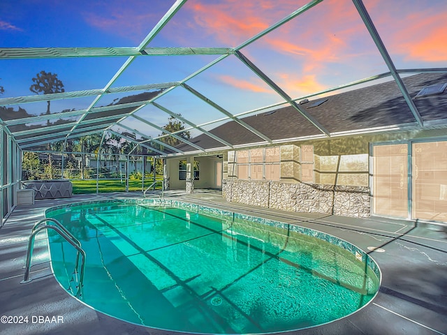 pool at dusk featuring a patio area and a lanai