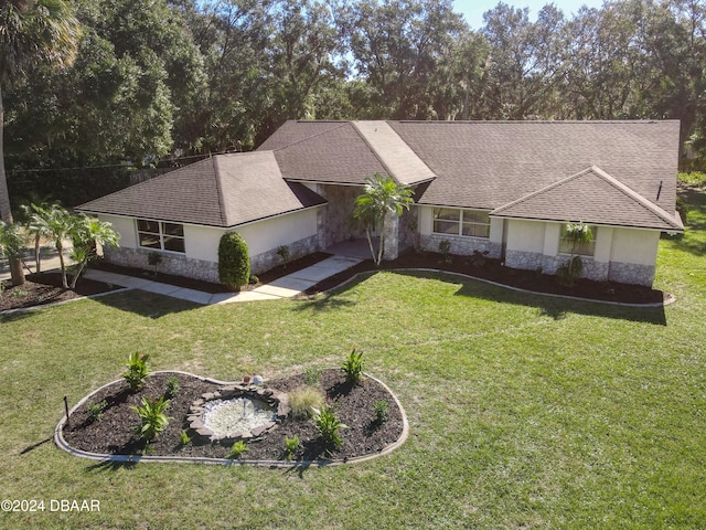 single story home with stone siding, a front yard, and roof with shingles