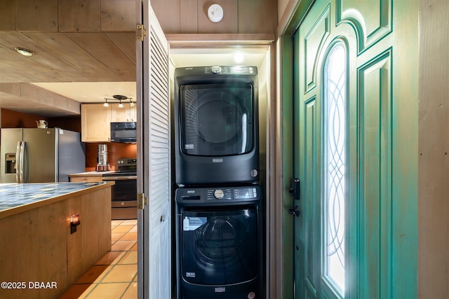 clothes washing area with light tile patterned flooring, laundry area, and stacked washer and dryer