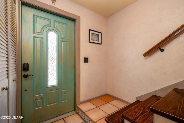 foyer entrance with light tile patterned floors, baseboards, and a textured wall