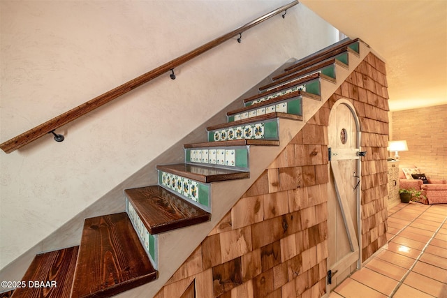 stairway featuring tile patterned floors and a textured wall