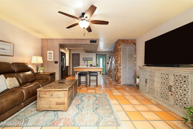 living area with light tile patterned floors, visible vents, and ceiling fan