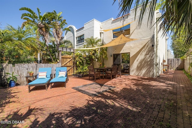 view of patio featuring outdoor dining area, a fenced backyard, and a gate