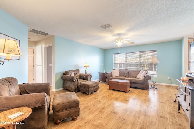 living room with a textured ceiling, light hardwood / wood-style floors, and ceiling fan