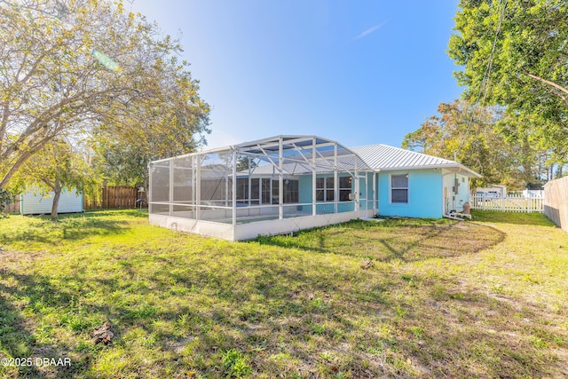 rear view of house with glass enclosure and a yard