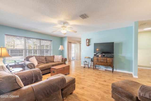 living room with ceiling fan, a textured ceiling, and light wood-type flooring