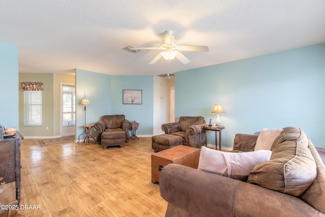 living room featuring ceiling fan, a textured ceiling, and light wood-type flooring