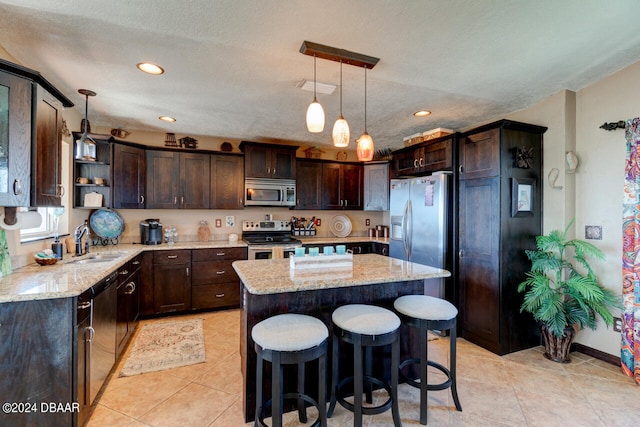 kitchen with sink, a textured ceiling, dark brown cabinets, a kitchen island, and stainless steel appliances