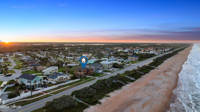 aerial view at dusk with a view of the beach and a water view