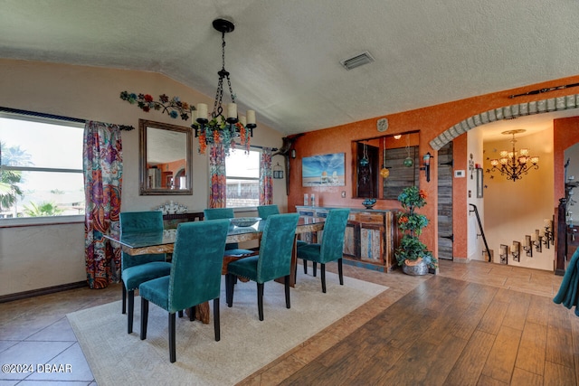 dining area with a textured ceiling, a chandelier, vaulted ceiling, and hardwood / wood-style flooring