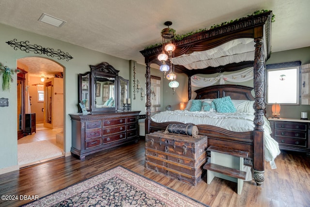 bedroom featuring a textured ceiling, dark hardwood / wood-style floors, and multiple windows