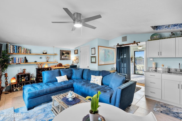 living room featuring ceiling fan, lofted ceiling, sink, and light tile patterned floors