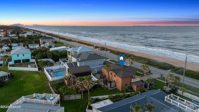 aerial view at dusk with a water view and a view of the beach