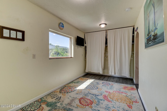 empty room with wood-type flooring and a textured ceiling