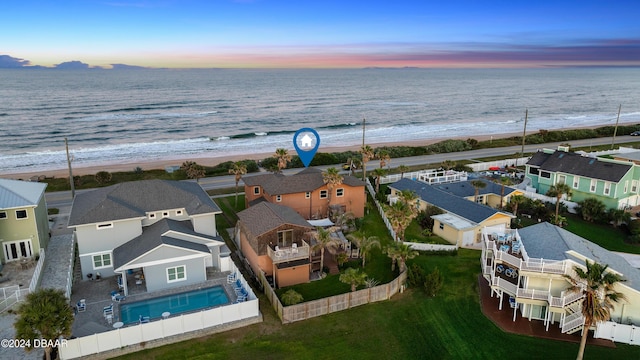 aerial view at dusk featuring a water view and a view of the beach