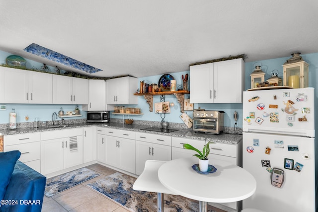 kitchen featuring white cabinetry, sink, white fridge, and light stone countertops