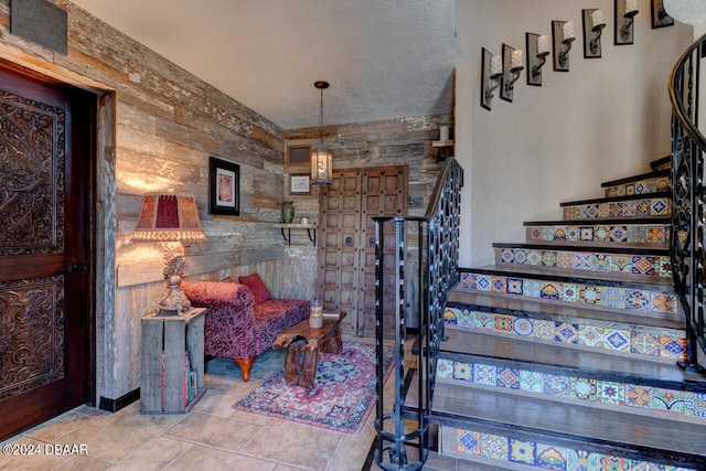 staircase featuring a textured ceiling and wooden walls