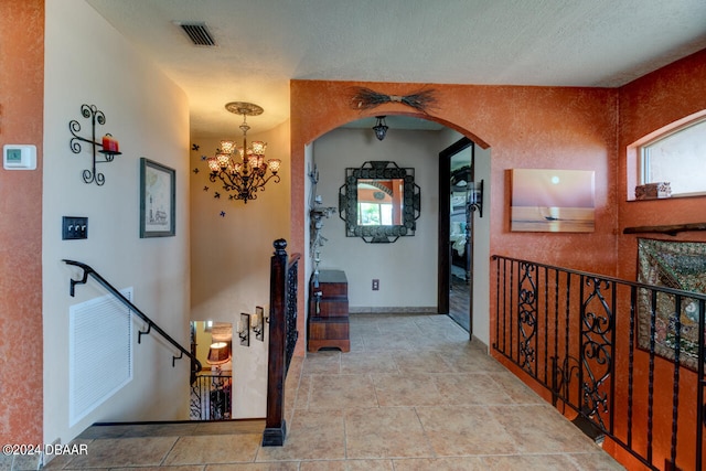 hall featuring a chandelier, a textured ceiling, and a wealth of natural light