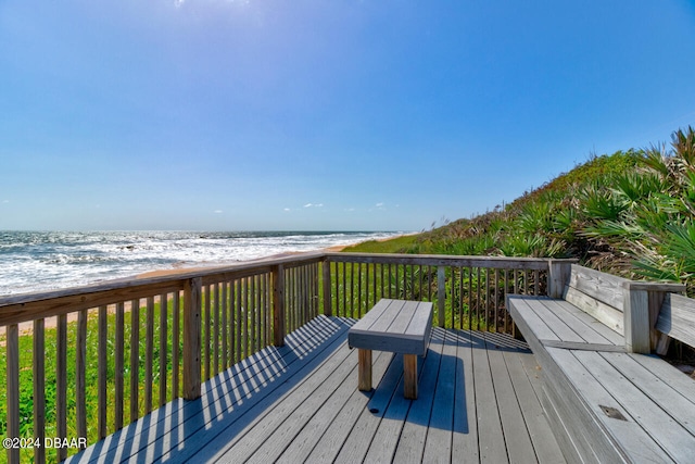 wooden deck featuring a water view and a view of the beach