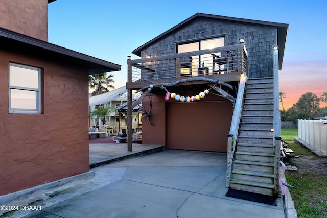 back house at dusk featuring a patio and a balcony