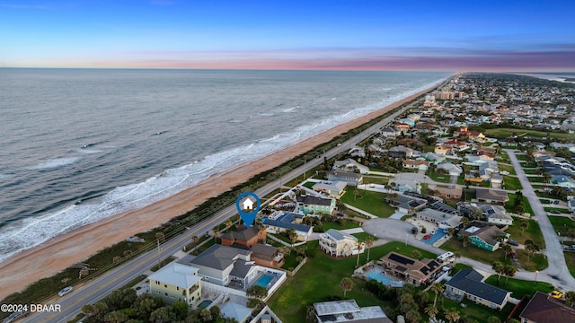 aerial view at dusk with a beach view and a water view