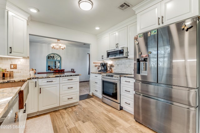 kitchen with stainless steel appliances, pendant lighting, white cabinets, and light stone counters