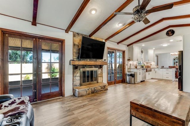 living room with sink, light hardwood / wood-style flooring, a fireplace, lofted ceiling with beams, and french doors