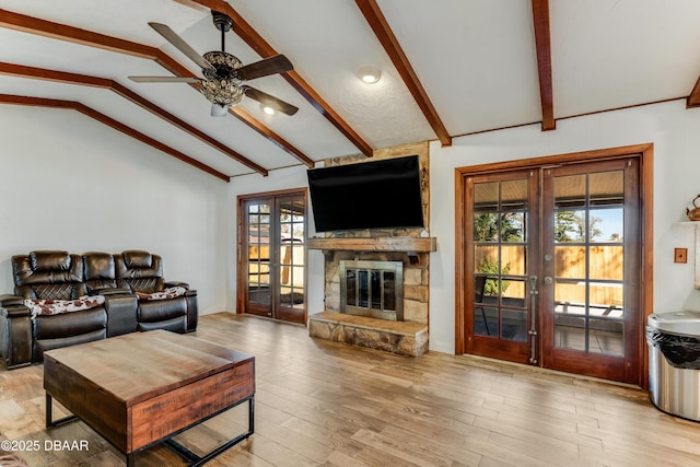 living room featuring french doors, a fireplace, lofted ceiling with beams, and light wood-type flooring