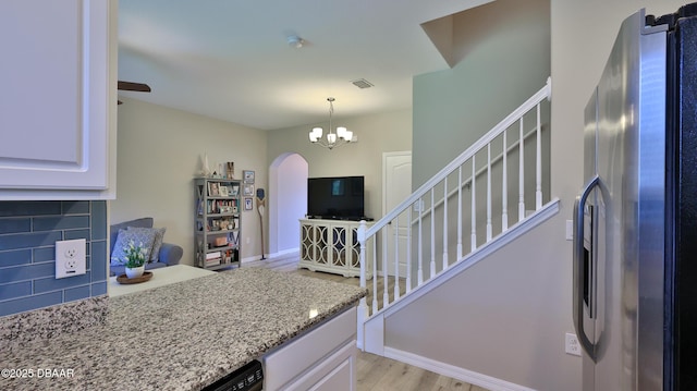 kitchen with white cabinets, light hardwood / wood-style flooring, stainless steel refrigerator with ice dispenser, and tasteful backsplash