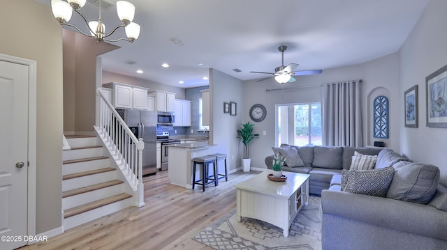 living room featuring ceiling fan with notable chandelier and light hardwood / wood-style floors