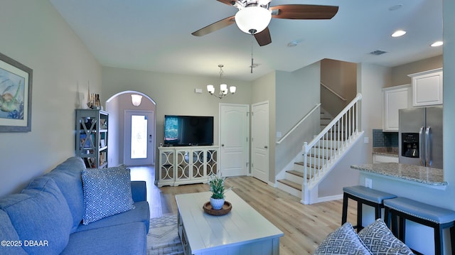 living room with light hardwood / wood-style floors and ceiling fan with notable chandelier