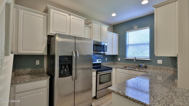 kitchen with white cabinets, backsplash, sink, and stainless steel appliances