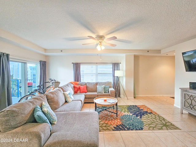 living room with a textured ceiling, plenty of natural light, light tile patterned floors, and ceiling fan