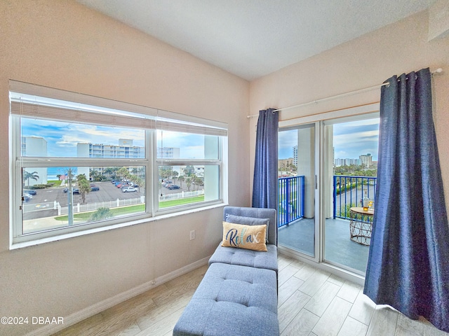 living area featuring a wealth of natural light, a water view, and light hardwood / wood-style flooring