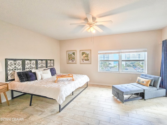 bedroom featuring ceiling fan, a textured ceiling, and light wood-type flooring