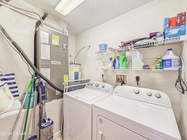 clothes washing area featuring water heater, a textured ceiling, and washer and dryer