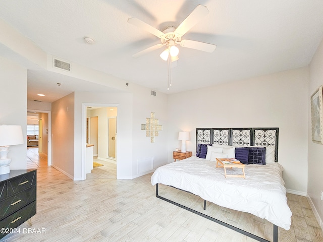 bedroom featuring light hardwood / wood-style floors, ceiling fan, and ensuite bath