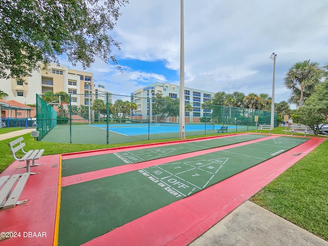 view of home's community featuring a lawn and tennis court