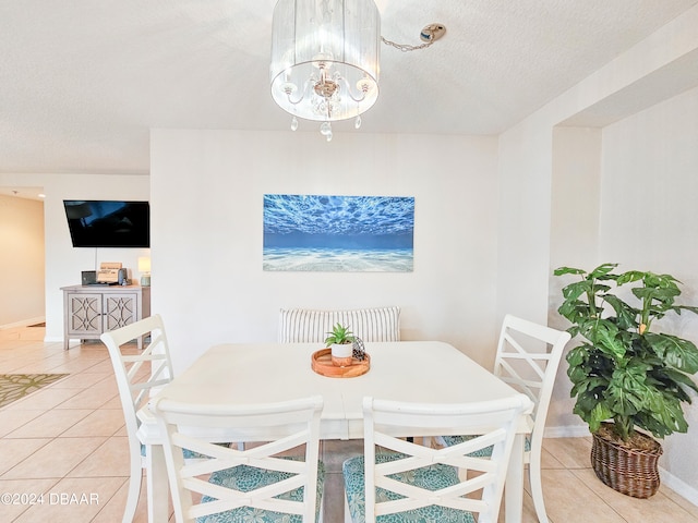 dining area featuring a textured ceiling, tile patterned floors, and an inviting chandelier