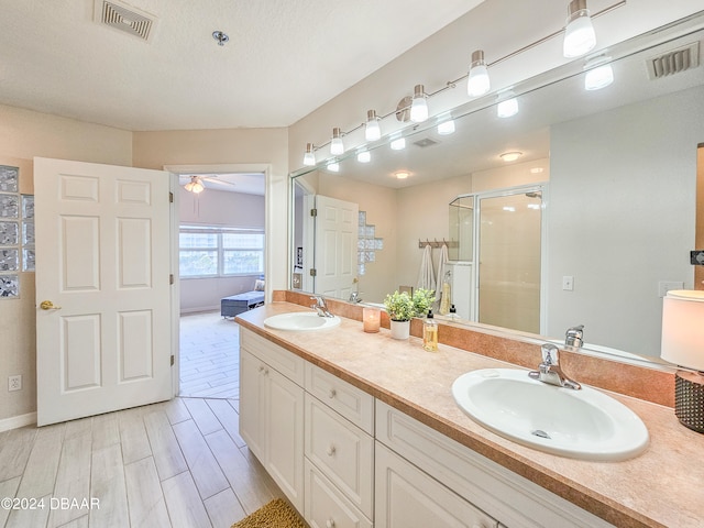 bathroom with a shower with door, vanity, a textured ceiling, hardwood / wood-style flooring, and ceiling fan