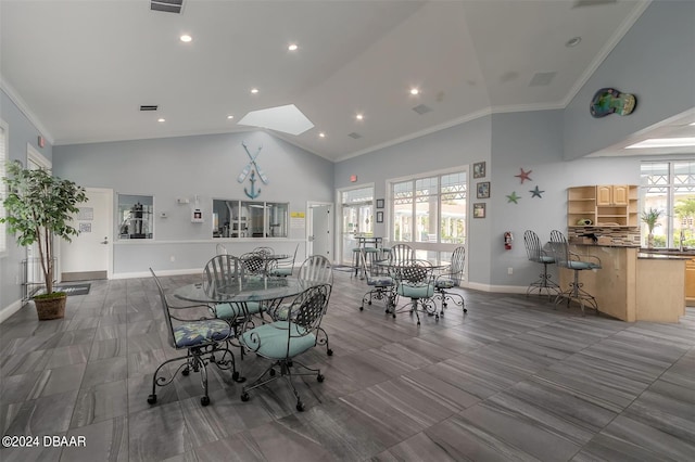 dining room featuring high vaulted ceiling, a skylight, and crown molding