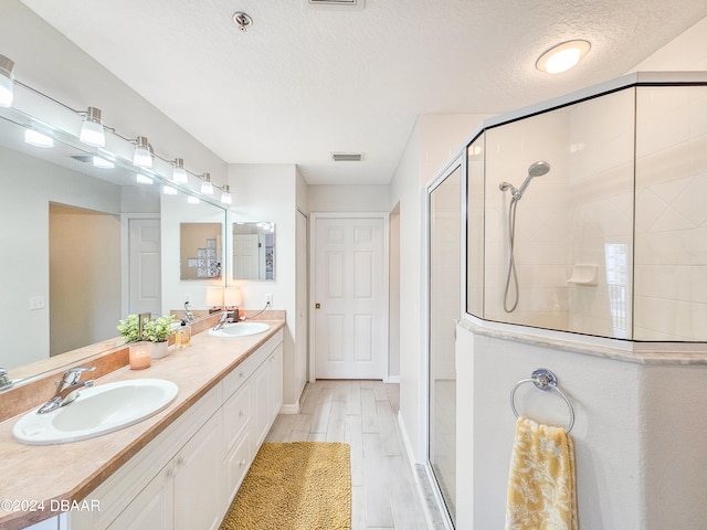 bathroom featuring hardwood / wood-style floors, vanity, a textured ceiling, and a shower with shower door