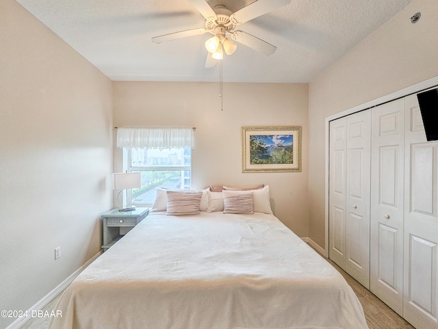 bedroom with ceiling fan, a textured ceiling, a closet, and light wood-type flooring