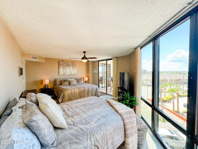 bedroom featuring access to outside, a wall of windows, ceiling fan, and a textured ceiling